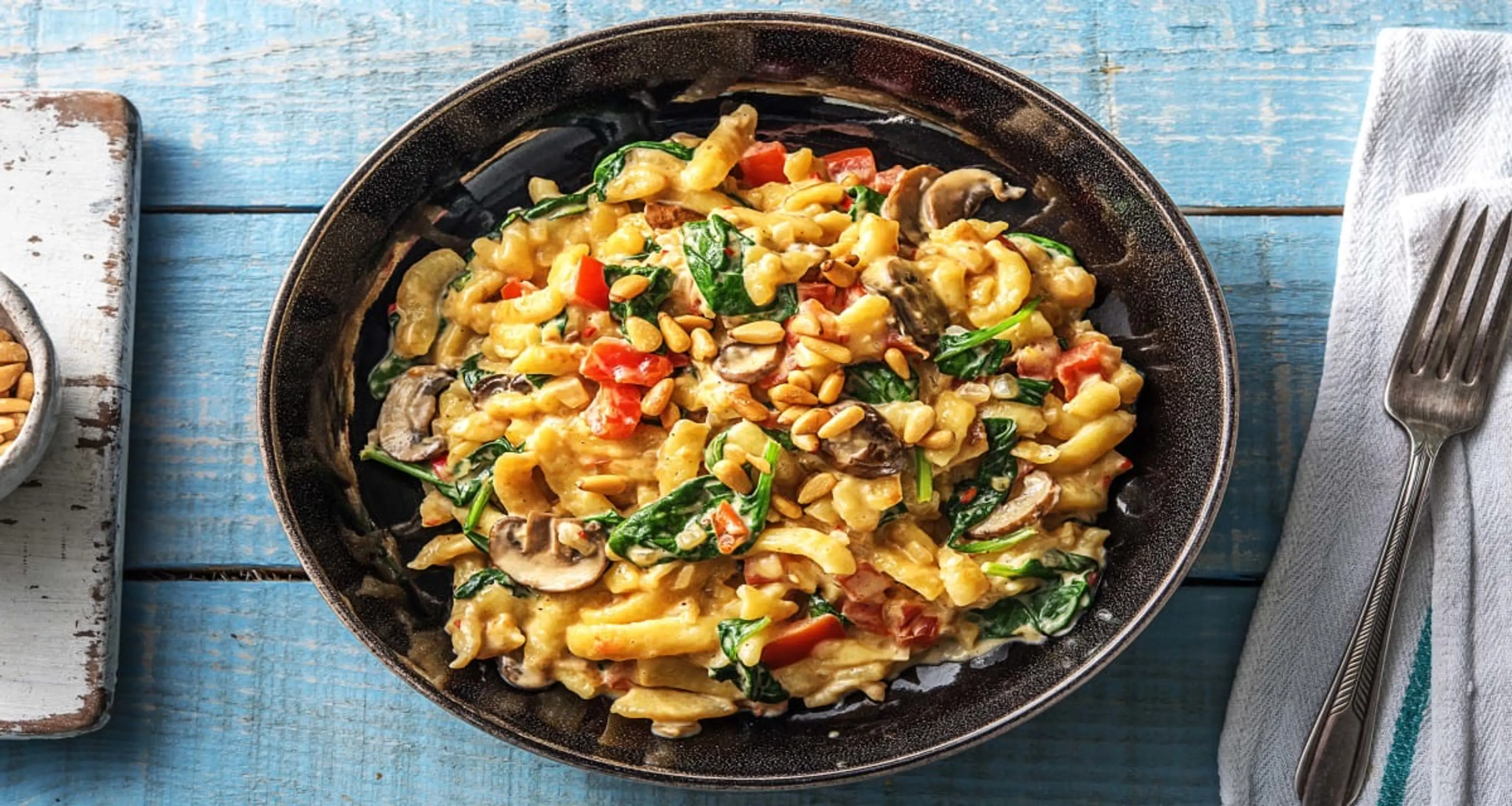 Cremige Spätzlepfanne mit Babyspinat und Pinienkernen