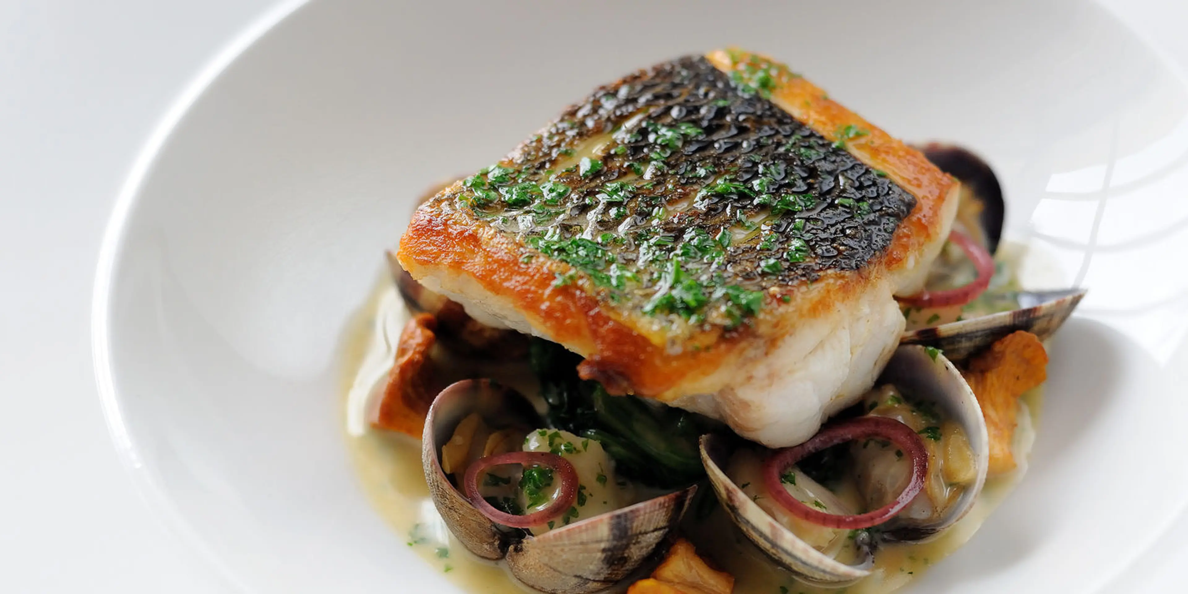 Pan-fried sea bass, butter spinach, clams, poached cod cheek | Umami